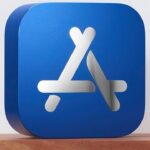 Blue cube with rounded edges featuring a white 3D overlapping sticks design resembling the App Store logo, placed on a wooden surface.