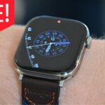 Apple Watch Series 11 on wrist with digital clock face displaying blue numbers; red