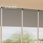 Four large gray roller shades partially open to reveal an outdoor scene with trees and a house. GE Smart Shades branding and logo are visible.