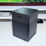 A UGREEN device is on a white desk, with a monitor and other electronics in the background.