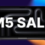 Open MacBook Pro laptop with abstract dark wavy screen pattern, bold white text M5 SALE across the center, set against a colorful blue, purple, and orange gradient background