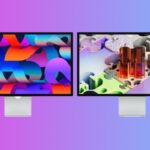 Two sleek desktop monitors side by side on a pinktoblue gradient background, each displaying colorful abstract digital artwork with vivid shapes and 3D forms