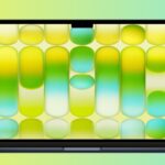 Open laptop with thin black bezel displaying colorful abstract wallpaper of rounded rectangles in yellow, green, and turquoise gradients against a soft yellow-to-teal gradient background